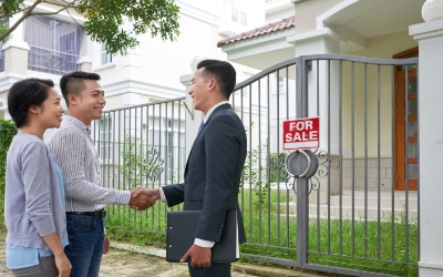 Agen properti berjabat tangan dengan klien di depan rumah