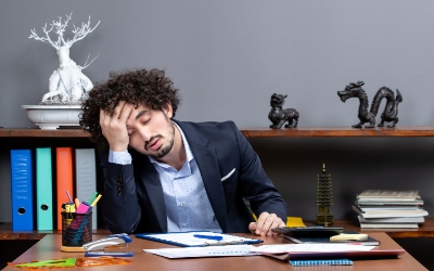 Seorang pria lelah dengan memegang kepala dan duduk di meja kantor (ww.freepik.com)